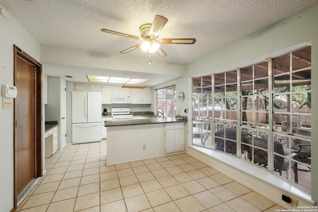 kitchen with white appliances, white cabinets, sink, light tile patterned floors, and kitchen peninsula