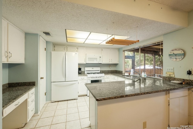 kitchen with kitchen peninsula, white appliances, white cabinetry, and dark stone counters