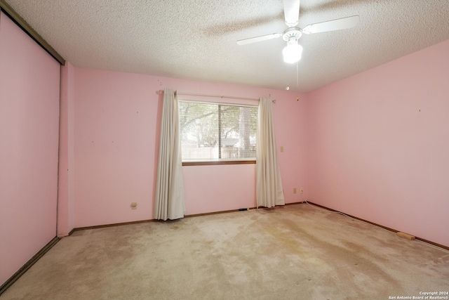 spare room with light carpet, ceiling fan, and a textured ceiling