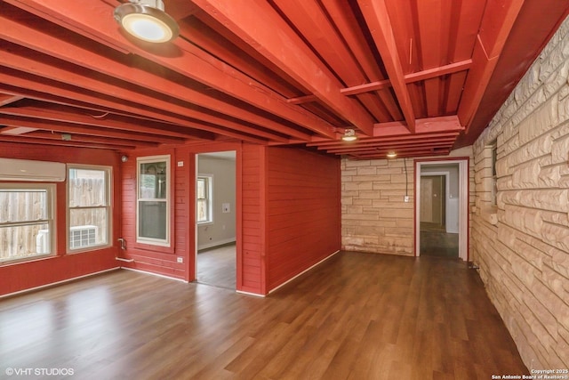 unfurnished room with beamed ceiling, a wall mounted air conditioner, dark wood-type flooring, and wood walls