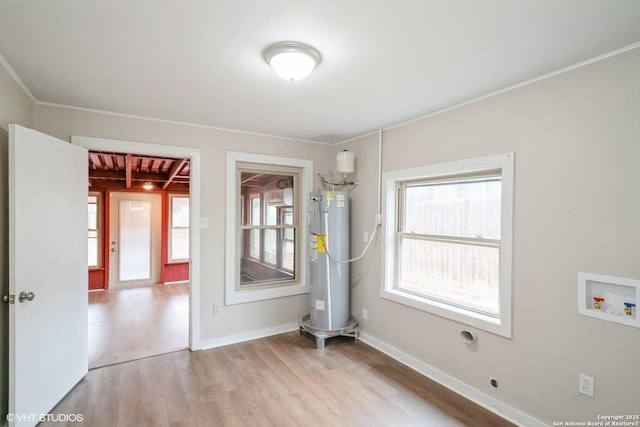 spare room with crown molding, electric water heater, and light wood-type flooring