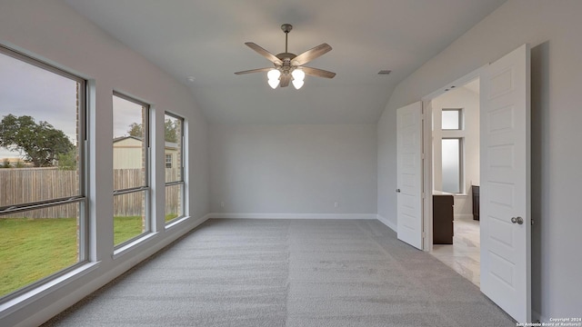 carpeted empty room featuring vaulted ceiling, ceiling fan, and a healthy amount of sunlight