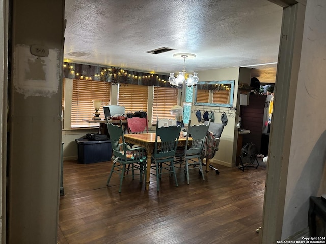 dining area with hardwood / wood-style flooring, a textured ceiling, and an inviting chandelier