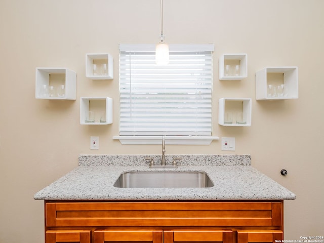 interior space featuring light stone countertops, sink, and pendant lighting