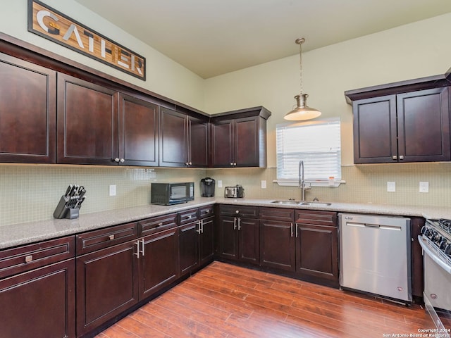 kitchen with backsplash, hanging light fixtures, wood-type flooring, appliances with stainless steel finishes, and sink