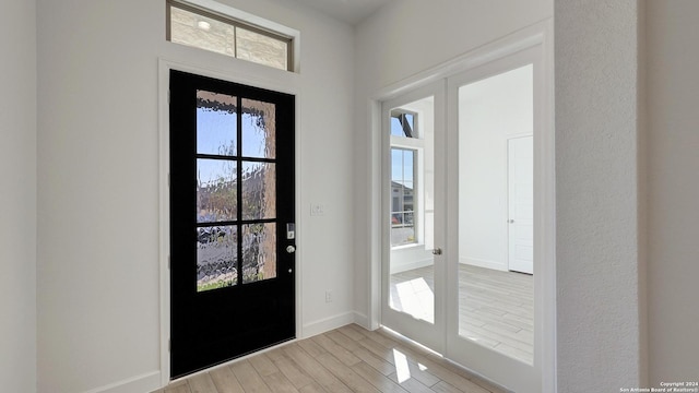 entrance foyer featuring french doors, light wood-type flooring, and a wealth of natural light