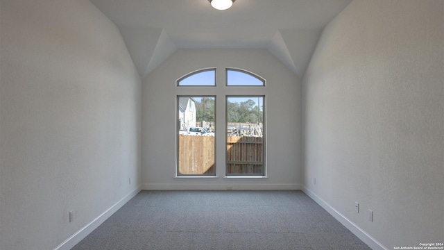 spare room with carpet flooring and lofted ceiling