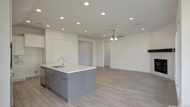 kitchen with white cabinetry, sink, ceiling fan, stainless steel dishwasher, and a kitchen island with sink