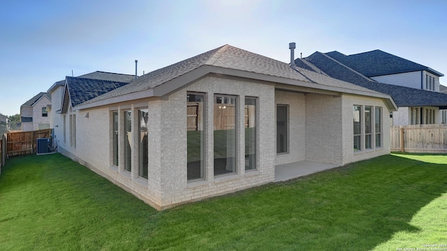 rear view of property with a lawn, central air condition unit, and a patio