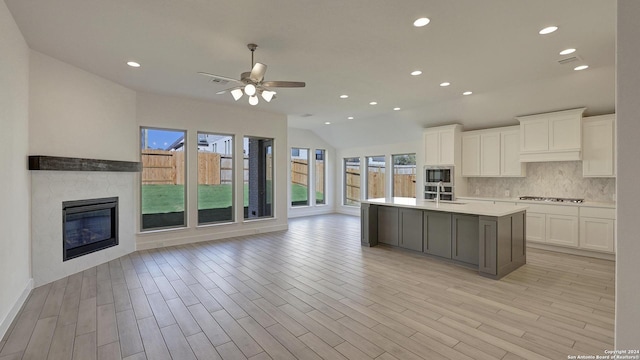 kitchen with sink, stainless steel appliances, light hardwood / wood-style floors, a center island with sink, and white cabinets