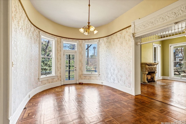 spare room with wallpapered walls, plenty of natural light, baseboards, and an inviting chandelier