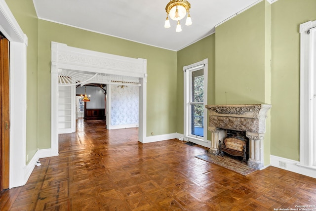 unfurnished living room featuring baseboards, a fireplace, a chandelier, and arched walkways