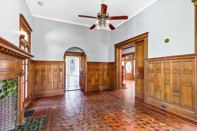 unfurnished living room with arched walkways, a wainscoted wall, plenty of natural light, and visible vents