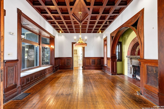 interior space featuring coffered ceiling, visible vents, a fireplace, and hardwood / wood-style flooring