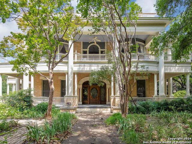 greek revival inspired property featuring covered porch and a balcony