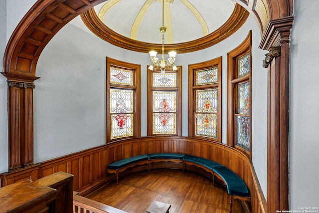 unfurnished room with arched walkways, a wainscoted wall, and a notable chandelier