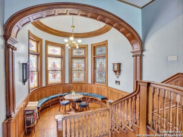 interior space with a wainscoted wall, wood finished floors, a chandelier, and crown molding