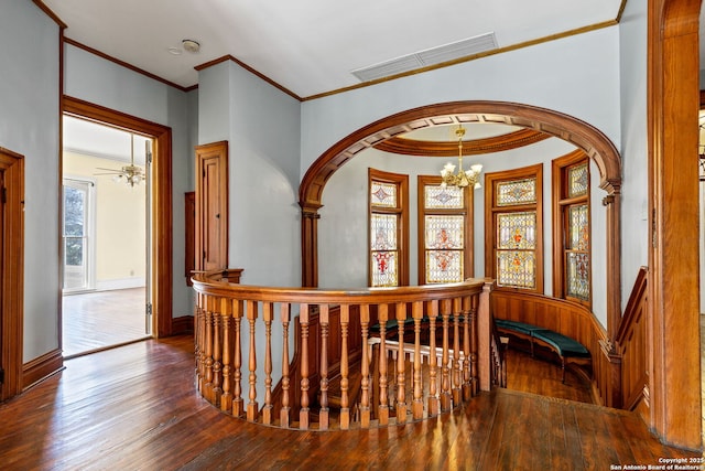 hallway with crown molding, visible vents, hardwood / wood-style floors, a chandelier, and baseboards