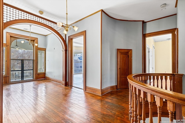 interior space with an inviting chandelier, crown molding, baseboards, and dark wood-type flooring