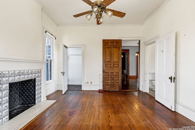 unfurnished living room with wood-type flooring, baseboards, crown molding, and a tile fireplace