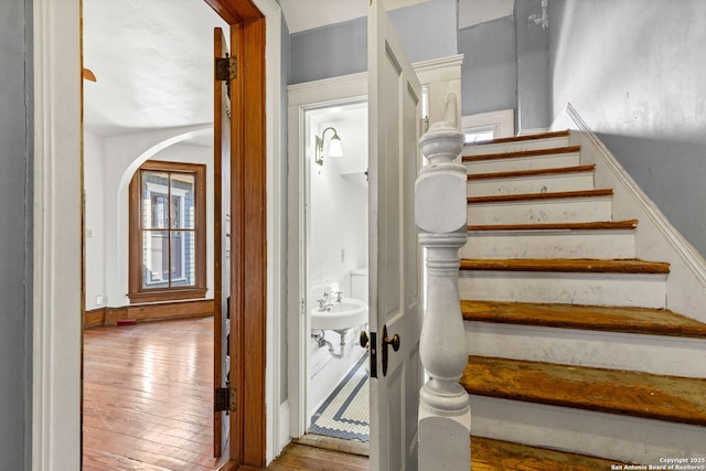 stairs featuring hardwood / wood-style flooring and arched walkways