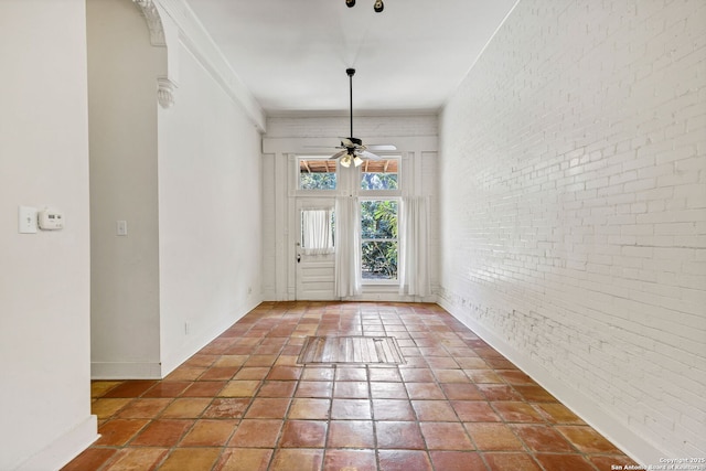 foyer entrance with brick wall, baseboards, a ceiling fan, and tile patterned floors