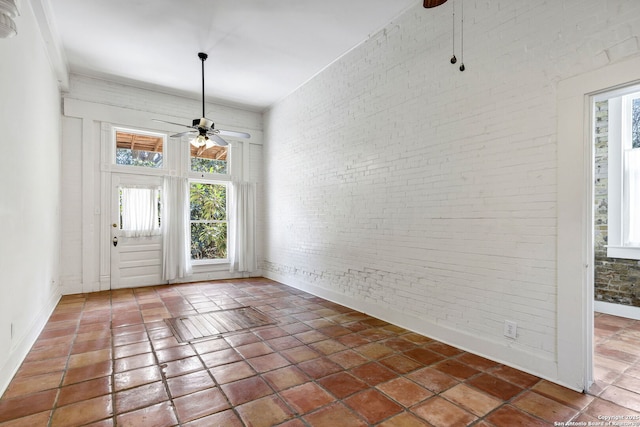 interior space featuring brick wall, a ceiling fan, and tile patterned floors