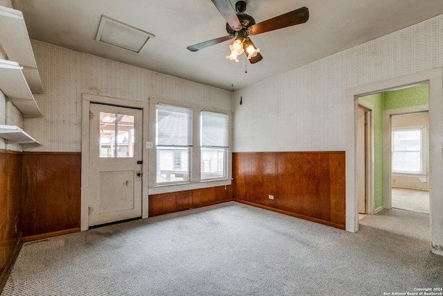 interior space featuring ceiling fan, light carpet, and wood walls