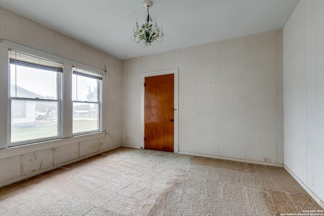 spare room with light carpet and a notable chandelier