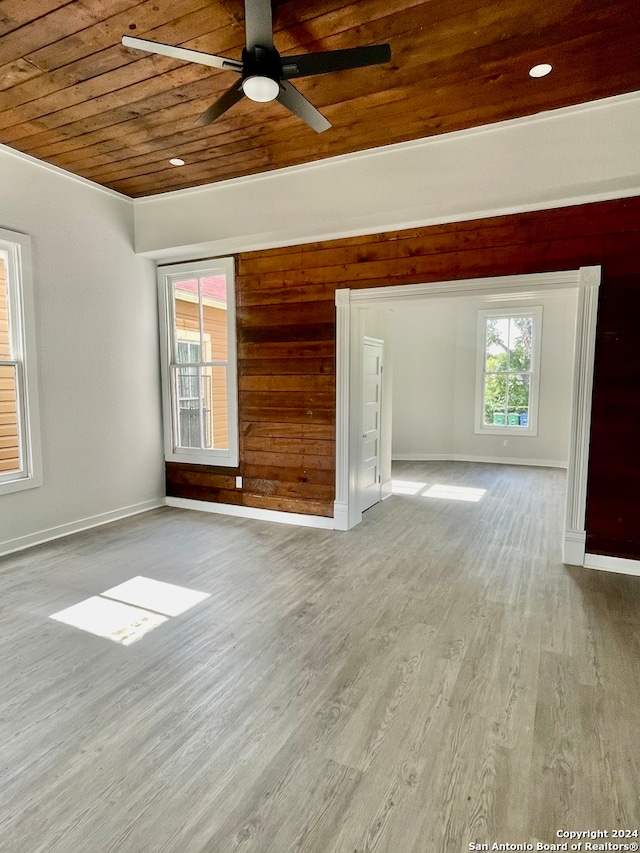 empty room featuring ornamental molding, wooden ceiling, hardwood / wood-style flooring, wooden walls, and ceiling fan