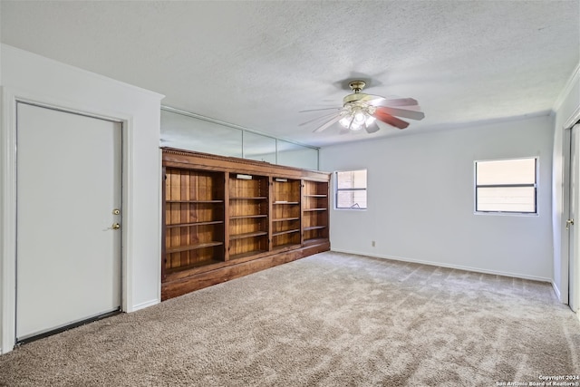 carpeted empty room featuring ceiling fan, crown molding, and a textured ceiling