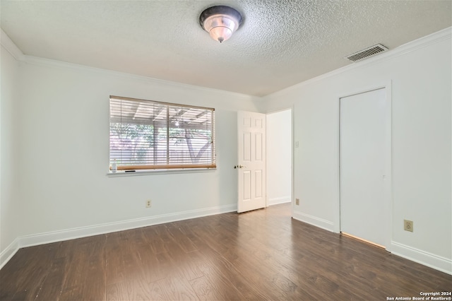 spare room featuring crown molding, dark wood-type flooring, and a textured ceiling