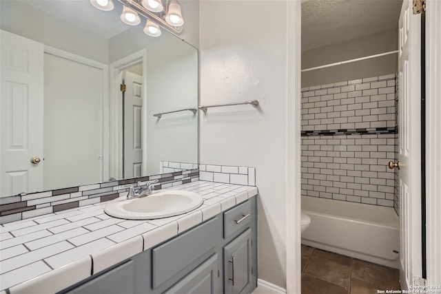 full bathroom with vanity, backsplash, tile patterned floors, tiled shower / bath combo, and toilet