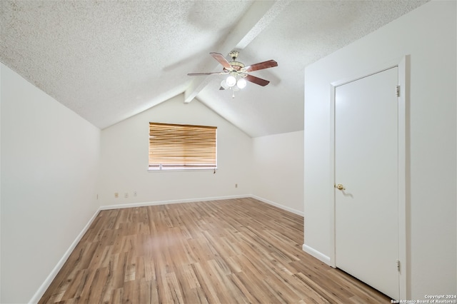 bonus room with ceiling fan, light hardwood / wood-style flooring, lofted ceiling with beams, and a textured ceiling