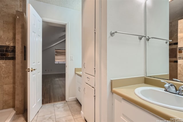 bathroom with a tile shower, vanity, and a textured ceiling