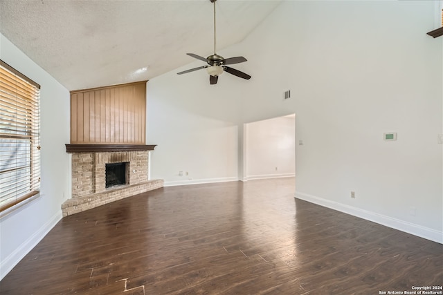 unfurnished living room with a textured ceiling, dark hardwood / wood-style floors, a brick fireplace, and ceiling fan