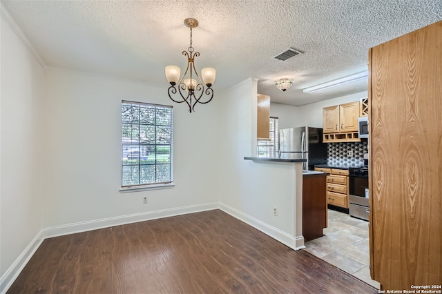 kitchen with decorative backsplash, stainless steel appliances, a chandelier, light hardwood / wood-style floors, and hanging light fixtures