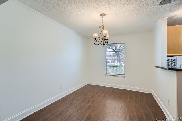 unfurnished dining area with a chandelier, a textured ceiling, dark hardwood / wood-style flooring, and ornamental molding