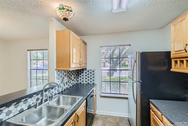 kitchen with backsplash, plenty of natural light, stainless steel fridge, and sink