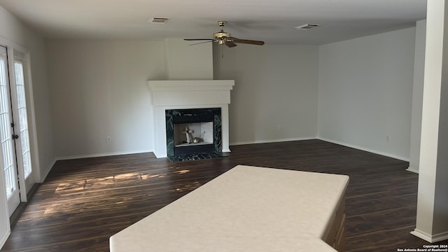 unfurnished living room featuring ceiling fan, dark wood-type flooring, and a high end fireplace