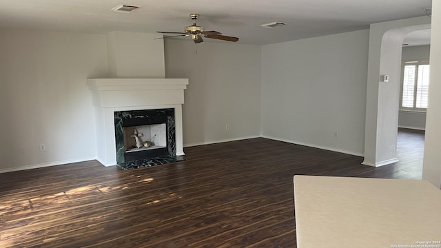 unfurnished living room with dark hardwood / wood-style flooring, ceiling fan, and a premium fireplace