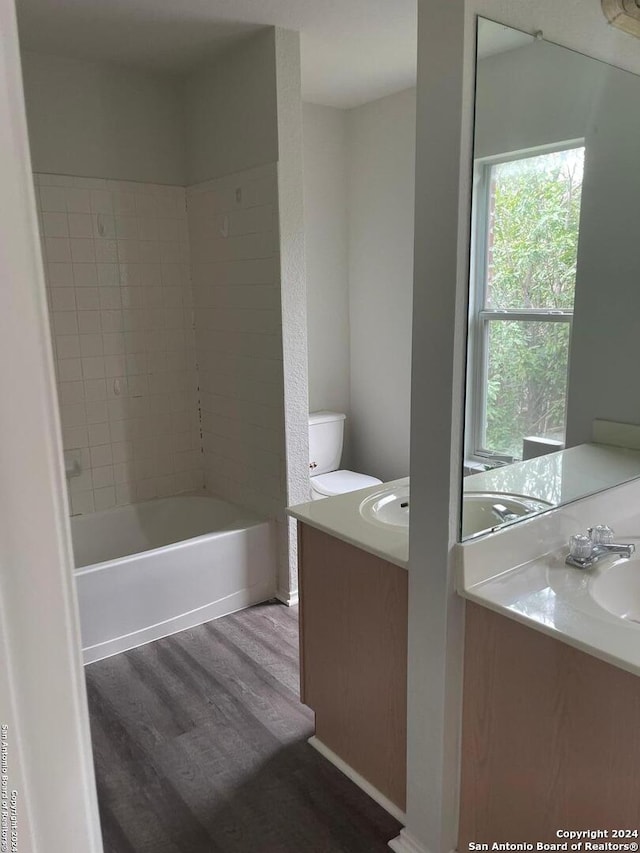 full bathroom featuring hardwood / wood-style floors, vanity, toilet, and tiled shower / bath