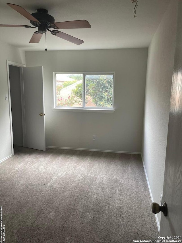 carpeted spare room featuring ceiling fan