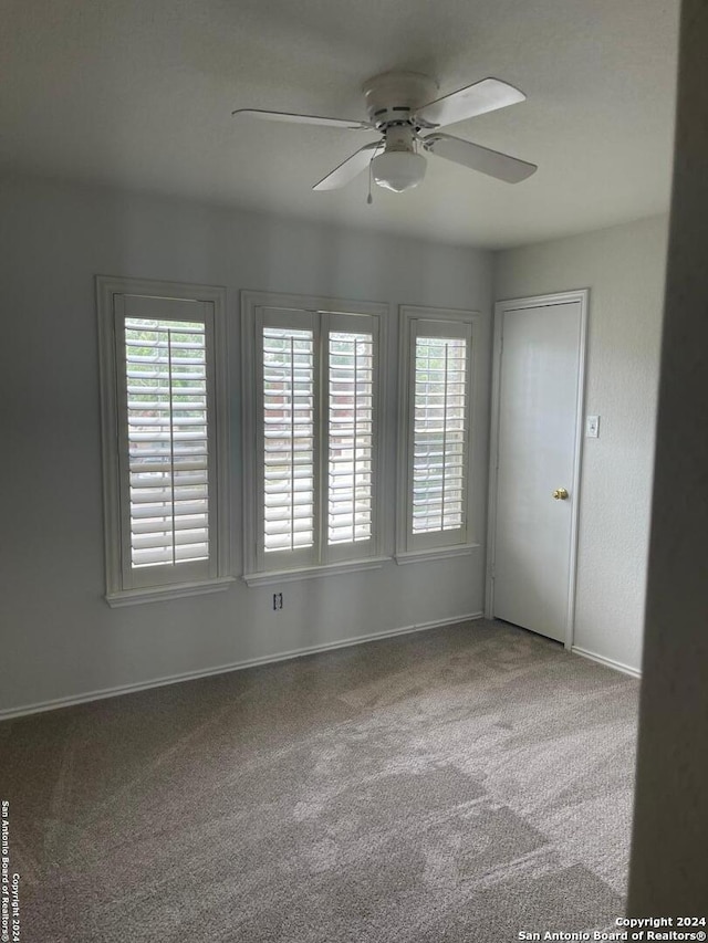 empty room featuring carpet, ceiling fan, and a healthy amount of sunlight