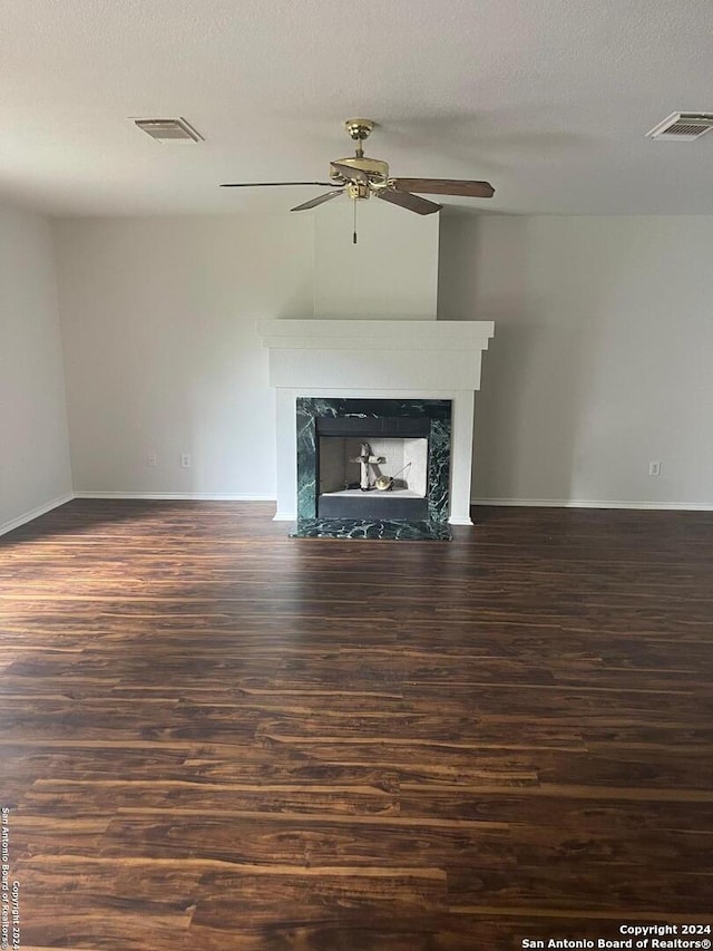 unfurnished living room with a textured ceiling, ceiling fan, a fireplace, and dark hardwood / wood-style floors