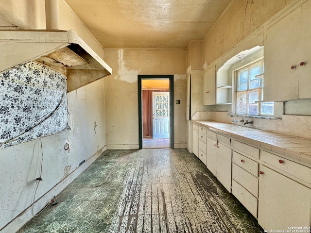 kitchen with tasteful backsplash, tile floors, sink, white cabinets, and tile countertops