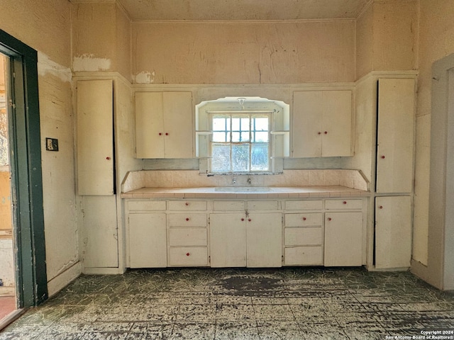 kitchen featuring white cabinets, sink, dark tile floors, and tile countertops