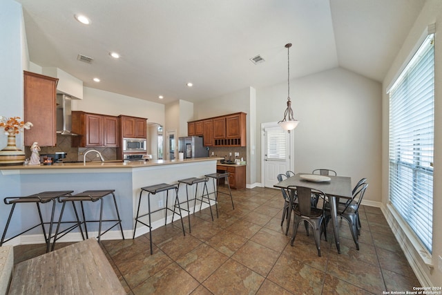 kitchen featuring appliances with stainless steel finishes, kitchen peninsula, a breakfast bar, and backsplash