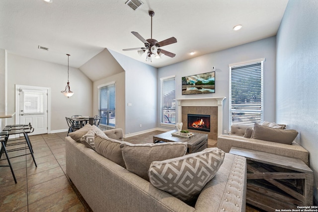 tiled living room featuring lofted ceiling, a tile fireplace, and ceiling fan