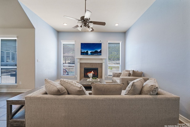 living room featuring hardwood / wood-style floors, a tiled fireplace, and ceiling fan